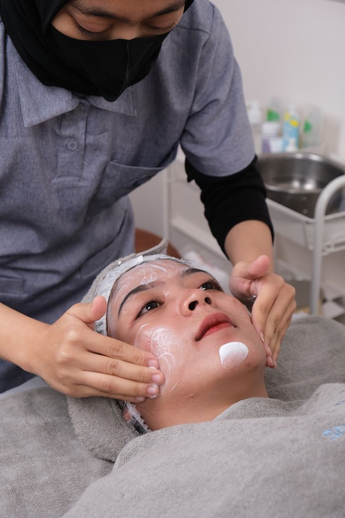 about-bg Skincare professional performing a soothing facial treatment on a client.