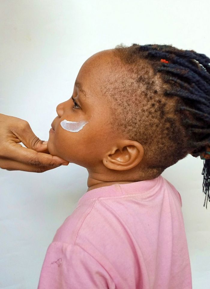 Mastering the First Impression: Your intriguing post title goes here Side profile of a child having facial cream applied, promoting skincare.
