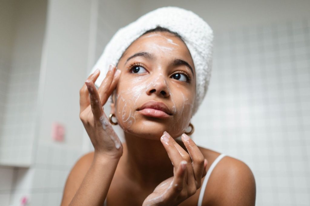 Consultation Form A young woman applies skincare cream in a modern bathroom setting.